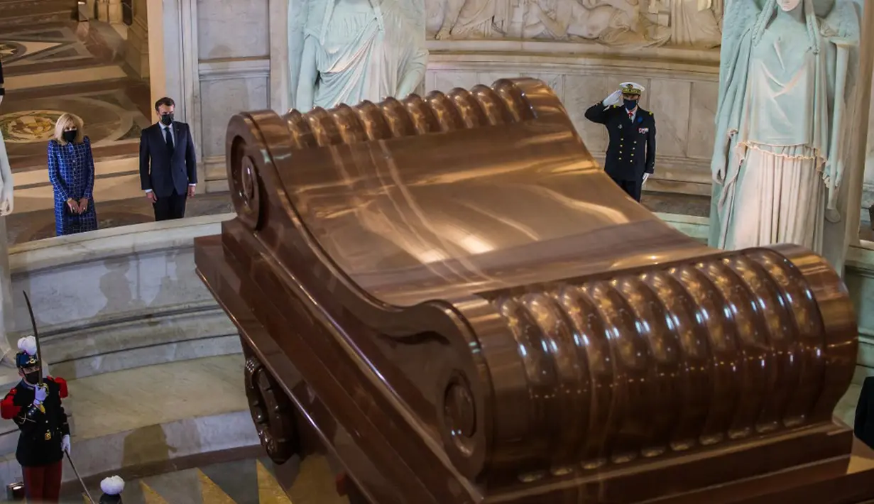 Presiden Prancis Emmanuel Macron dan istrinya Brigitte Macron berdiri di depan makam Kaisar Prancis Napoleon (1769-1821) saat upacara peringatan 200 tahun kematiannya di Chapelle Saint-Jerome, Invalides, Paris, Prancis, Rabu (5/5/2021). (Christophe PETIT TESSON/POOL/AFP)
