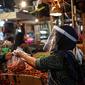 Salah satu pedagang menggunakan face shield dan sarung tangan saat melayani pembeli di Pasar Senen, Jakarta, Senin (1/6/2020). Saat era new normal, para pedagang di pasar rakyat diwajibkan menggunakan masker, face shield, dan sarung tangan selama beraktivitas. (Liputan6.com/Faizal Fanani)