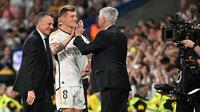 Pemain Real Madrid, Toni Kroos (tengah) menyalami pelatih Carlo Ancelotti saat upacara perpisahan setelah laga Liga Spanyol 2023/2024 melawan Real Betis di Santiago Bernabeu, Madrid, Spanyol, Minggu (26/05/2024) dini hari WIB. Kroos memutuskan untuk pensiun dari sepak bola setelah Euro 2024 nanti. (AFP/Javier Soriano)