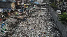 Pandangan udara menunjukkan anak-anak berdiri di dekat saluran pembuangan air yang dipenuhi sampah di lingkungan berpenghasilan rendah di New Delhi, India (4/10/2019). (AFP Photo/Noemi Cassanelli)