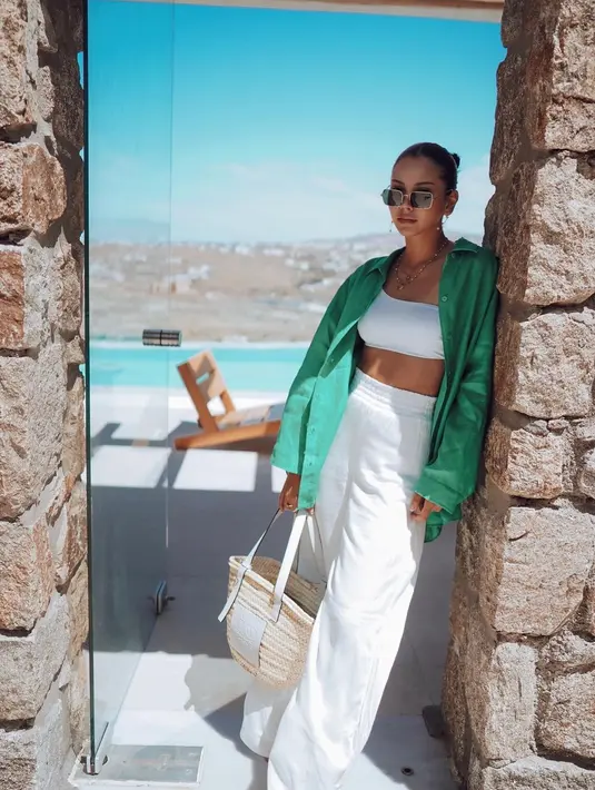 <p>Bisa jadi inspirasi outfit ke pantai, padukan celana putih dengan one shoulder crop top. Bila ingin melengkapi penampilan, tambahkan kemeja oversized dengan warna kontras. [Instagram/alyssadaguise]</p>