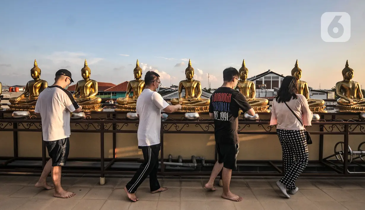 Jemaat saat memberikan koin pada 108 patung Buddha saat peringatan Tri Suci Waisak 2565 BE di Vihara Hemadhiro Mettavati, Cengkareng, Jakarta Barat, Rabu (26/5/2021). (merdeka.com/Iqbal S. Nugroho)