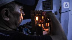 Jimmy Alexander (52) memberikan lampu pada miniatur rumah yang dibuatnya saat menyelesaikan pembuatan kerajinan miniatur di kawasan Kalipasir Dalam, Cikini, Jakarta Pusat, Senin (5/9/2022). Untuk pembuatan, Jimmy membutuhkan waktu 4-10 hari dalam menyelesaikan miniatur, tergantung tingkat kesulitan. (merdeka.com/Iqbal S Nugroho)