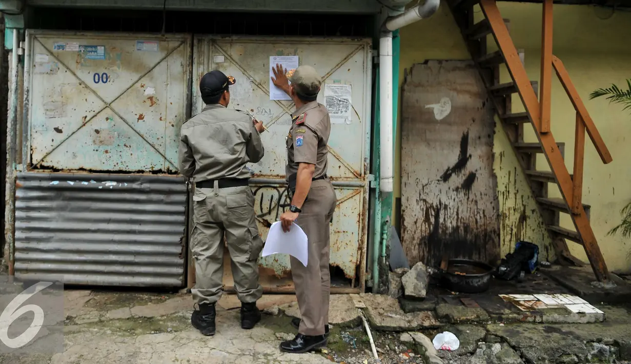 Petugas satpol PP menempel surat peringatan ke 3 di Kawasan Bukit Duri, Jakarta, Selasa (20/9). Pemkot Jaksel akan menertibkan bangunan dan permukiman di kawasan Bukit Duri yang berbatasan dengan Sungai Ciliwung. (Liputan6.com/Gempur M Surya)