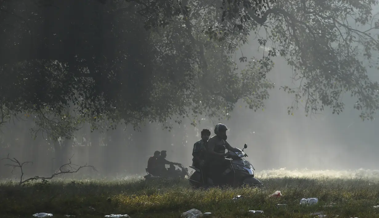 Pengendara motor melintas saat pagi yang berkabut di taman Maidan di Kolkata (29/11/2019). Maidan  merupakan taman bandar terbesar di Kolkata di negeri dalam India di Bengal Barat. (AFP Photo/Dibyangshu Sarkar)