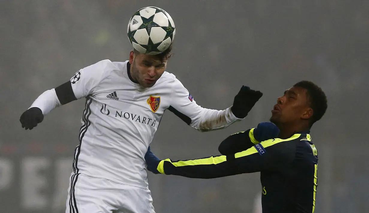 Penyerang FC Basel, Renato Steffen, duel udara dengan penyerang Arsenal, Alex Iwobi. Kemenangan ini mengantar Arsenal menjadi juara Grup A, unggul dua poin dari PSG pada posisi kedua. (Reuters/Arnd Wiegmann)