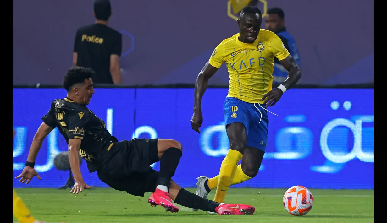 Pemain Al Nassr, Sadio Mane (kanan), berusaha melewati hadangan pemain Al Taawon dalam laga pekan ke-2 Liga Arab Saudi 2023/2024 yang berlangsung di KSU Football Stadium, Sabtu (19/8/2023) dini hari WIB. (AFP/Fayez Nureldine)