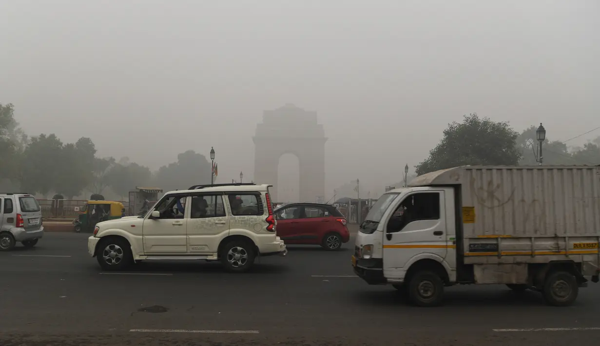 Kendaraan bermotor melintasi India Gate yang diselimuti kabut asap pekat di New Delhi, Minggu (3/10/2019). Polusi di New Delhi disebabkan asap kembang api dalam Festival Diwali dan kabut asap akibat pembukaan lahan di pinggiran kota dan negara bagian di sekitarnya. (Photo by Sajjad  HUSSAIN / AFP)