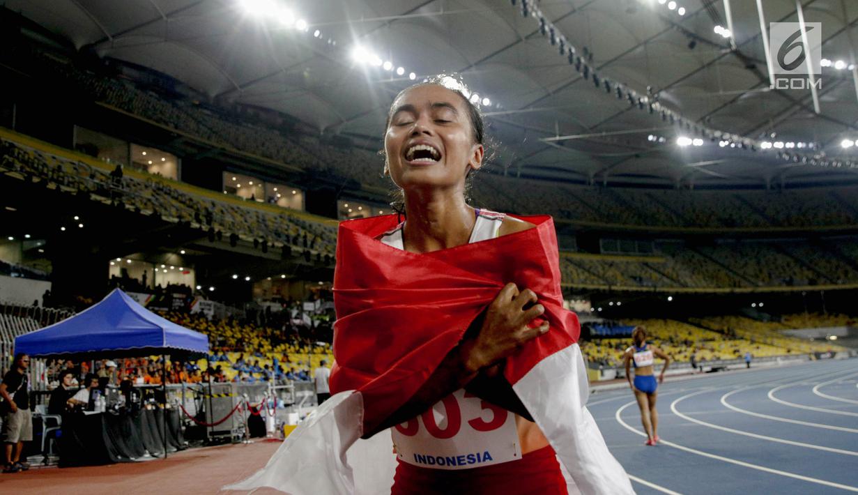 Pelari Indonesia Triyaningsih membawa bendera merah putih setelah mencapai garis finis dalam cabang olahraga atletik nomor lari 10 km putri SEA Games 2017 di Stadion Nasional Bukit Jalil, Malaysia, Kamis (24/8). (Liputan6.com/Faizal Fanani)