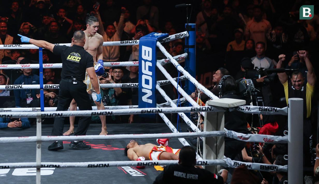 Petarung Indonesia, Serieal Effendy, terkapar setelah mendapatkan tendangan keras dari petarung Malaysia, Ammarul Shafiq, pada pertandingan Byon Combat Showbiz Vol. 6 di Tennis Indoor Senayan, Jakarta, Sabtu (22/10/2025). (Bola.com/M Iqbal Ichsan)