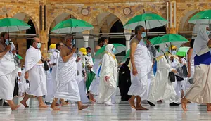 Jemaah yang memegang payung untuk melindungi diri dari panas tiba di Masjidil Haram pada awal musim haji, Arab Saudi, Sabtu (17/7/2021). Pemerintah Arab Saudi mengklaim ibadah haji tahun lalu hanya diikuti 1.000 orang, sementara media lokal menyebut ada 10 ribu orang. (FAYEZ NURELDINE/AFP)