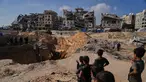 Warga Palestina menyaksikan aktivitas pekerja Mesir yang menggunakan alat berat untuk mencari jenazah para sandera di Kota Hamad, Khan Younis, di Jalur Gaza selatan, Selasa 28 Oktober 2025. (AP Photo/Abdel Kareem Hana)