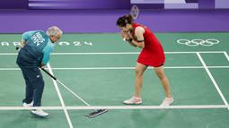 Seorang volunter sedang memberishkan keringan pebulu tangkis putri Thailand, Ratchanok Intanon saat pertandingan grup Olimpiade Paris 2024 melawan atlet Belgia, Lianne Tan di Porte de la Chapelle Arena, Paris, Prancis pada 30 Juli 2024. (AFP/Luis Tato)