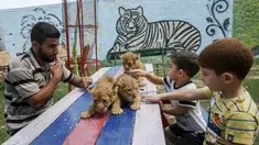 Anak-anak Palestina didampingi seorang pekerja bermain dengan tiga bayi singa yang baru lahir di sebuah kebun binatang di Rafah, Jalur Gaza (8/9/2019). Kehadiran tiga bayi singa ini menambah koleksi satwa sebuah kebun binatang tersebut. (AFP Photo/Said Khatib)