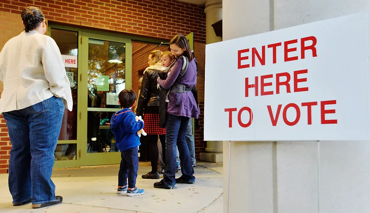 Warga mengajak anaknya saat akan melakukan pemilihan presiden AS di Durham, North Carolina, AS, Selasa (8/11). Warga AS akan menentukan presiden mereka antara Hillary Clinton dan Donald Trump. (AFP Photo/ Sara D. Davis)