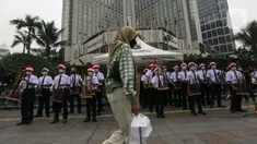 Seorang wanita berjalan di depan para peserta yang sedang bermain angklung saat acara Christmas in Jakarta di Bundaran Hotel Indonesia, Jakarta, Selasa (21/12/2021). Pemerintah Provinsi DKI Jakarta menggelar Christmas in Jakarta dalam rangka menyambut Natal 2021. (Liputan6.com/Johan Tallo)