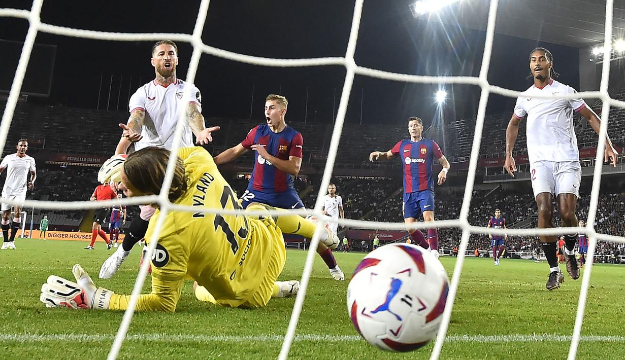 Pemain Sevilla, Sergio Ramos (kedua kiri) mencetak gol bunuh diri ke gawangnya sendiri saat laga lanjutan Liga Spanyol 2023/2024 melawan Barcelona di Estadi Olimpic Lluis Companys, Barcelona, Spanyol, Sabtu (30/09/2023) dini hari WIB. Sevilla kalah dengan skor 0-1 melalui gol tersebut. (AFP/Pau Barrena)