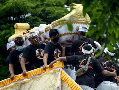 Orang-orang membawa jenazah mendiang Raja Ida Cokorda Pemecutan XI atau Anak Agung Ngurah Manik Parasara saat upacara ngaben di Denpasar, Bali, 21 Januari 2022. Anak Agung Ngurah Manik Parasara meninggal pada Desember lalu di usia 76 tahun. (SONY TUMBELAKA/AFP)