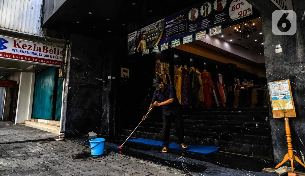 Seorang pria mengepel pintu masuk sebuah toko di kawasan perdagangan Pasar Baru, Jakarta, Jumat (3/4/2020). Sebagian pemilik toko di Pasar Baru memilih menutup usahanya sementara waktu untuk mengantisipasi meluasnya penyebaran virus corona COVID-19. (Liputan6.com/Faizal Fanani)