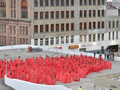 Ratusan orang berpose mengenakan kain merah transparan saat foto bugil massal dari proyek terbaru fotografer AS Spencer Tunick di tempat parkir mobil di pusat perbelanjaan di Melbourne, Australia (9/7). (AFP Photo/Paul Crock)