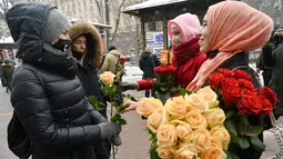 Aktivis Asosiasi Perempuan Muslim Ukraina memberikan bunga kepada pejalan kaki selama perayaan World Hijab Day atau Hari Hijab Sedunia di pusat kota Kiev, Senin (1/2/2021). Hari Hijab Sedunia merupakan gagasan Nazma Khan di New York, Amerika Serikat pada tahun 2013. (Sergei SUPINSKY/AFP)