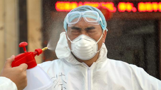Pekerja berpakaian pelindung didesinfeksi di luar hotel yang digunakan dalam isolasi medis virus corona di Wuhan, Provinsi Hubei, China, Senin (3/2/2020). (Chinatopix via AP)
