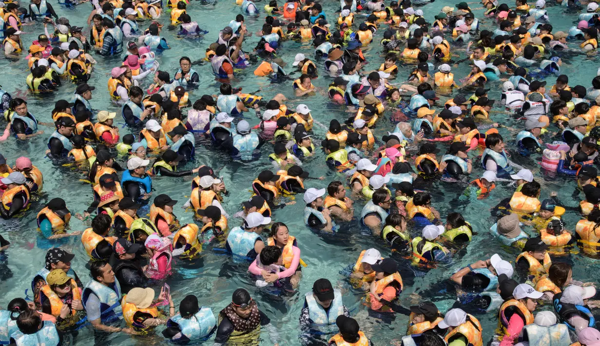 Wisatawan memadati water park yang dikenal dengan Caribbean Bay di Yongin, luar Seoul, Senin (6/8). Gelombang panas yang melanda Korea Selatan akhir-akhir ini membuat ratusan warga memenuhi kolam renang untuk mengurangi hawa panas. (Ed JONES/AFP)