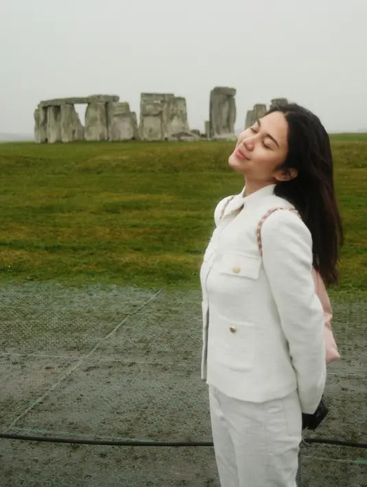Terbaru, Azizah tampil dengan outfit serba putih di Stonehenge. Ia kenakan tweed blazer dengan celana putih dan kupluk rajut berbentuk beruang [@azizahsalsha_]