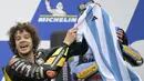 <p>Pebalap Tim Mooney VR46, Marco Bezzecchi merayakan kemenangan dengan jersey Timnas Argentina bertandatangan Lionel Messi saat menjuarai MotoGP Argentina 2023 di Aut&oacute;dromo Termas de R&iacute;o Hondo, Argentina, Senin (03/04/2023) dini hari WIB. Selebrasi tersebut diketahui meniru sang gurunya, Valentino Rossi yang dilakukan pada musim 2015 silam. (AFP/Juan Mabromata)</p>