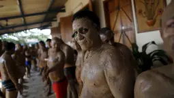 Seorang tahanan melumuri badannya dengan lumpur selama mengikuti terapi tanah liat di penjara Porto Velho, Brasil, (28/8/2015) . Kegiatan yang dilakukan seperti bermain bersama, pijat refleksi, pengetahuan spritual dll. (REUTERS/Nacho Doce) 