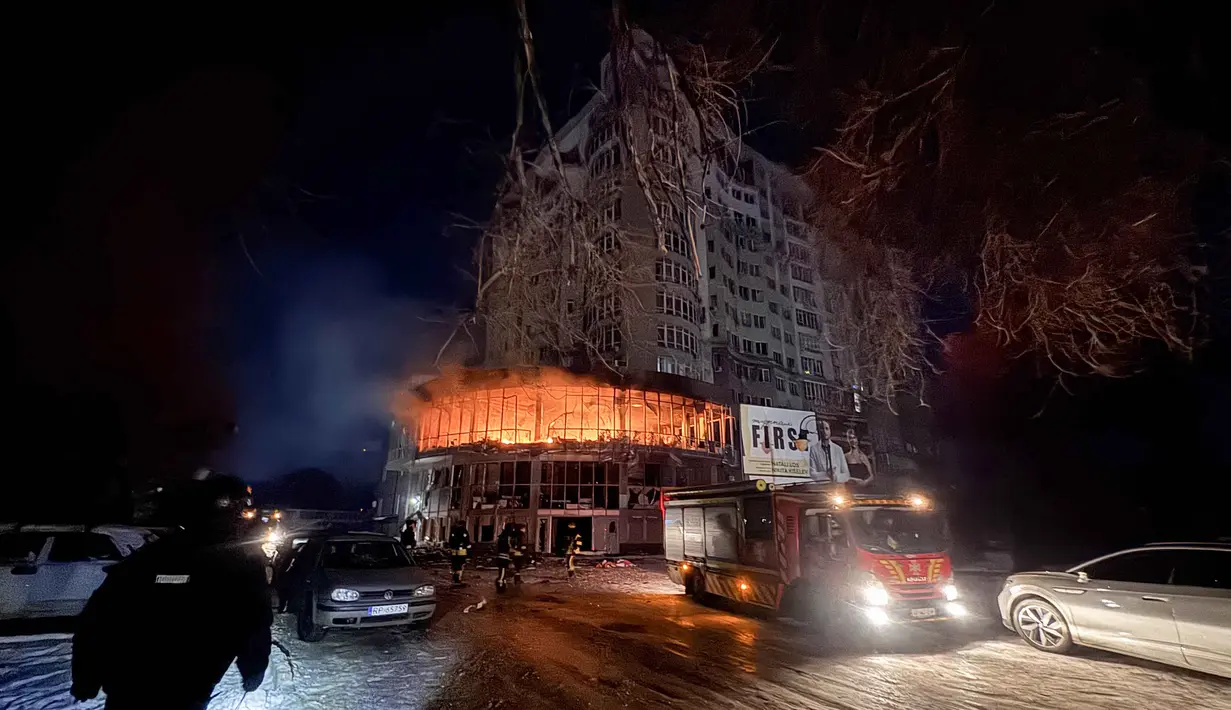 Petugas pemadam kebakaran berdiri di dekat bangunan tempat tinggal yang terbakar setelah serangan pesawat tak berawak Rusia di Zaporizhzhia pada 2 Januari 2026, di tengah invasi Rusia ke Ukraina. Rusia melancarkan serangan udaranya ke wilayah Zaporizhzhia, Ukraina. (Darya NAZAROVA/AFP)
