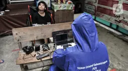 Petugas Disdukcapil Kota Jakarta Utara merekam E-KTP penyandang disabilitas di Pademangan Barat, Jakarta, Kamis (16/7/2020). Program jemput bola ini untuk memudahkan pelayanan administrasi kependudukan bagi penyandang disabilitas, jompo dan orang sakit di masa pandemi. (merdeka.com/Iqbal S. Nugroho)