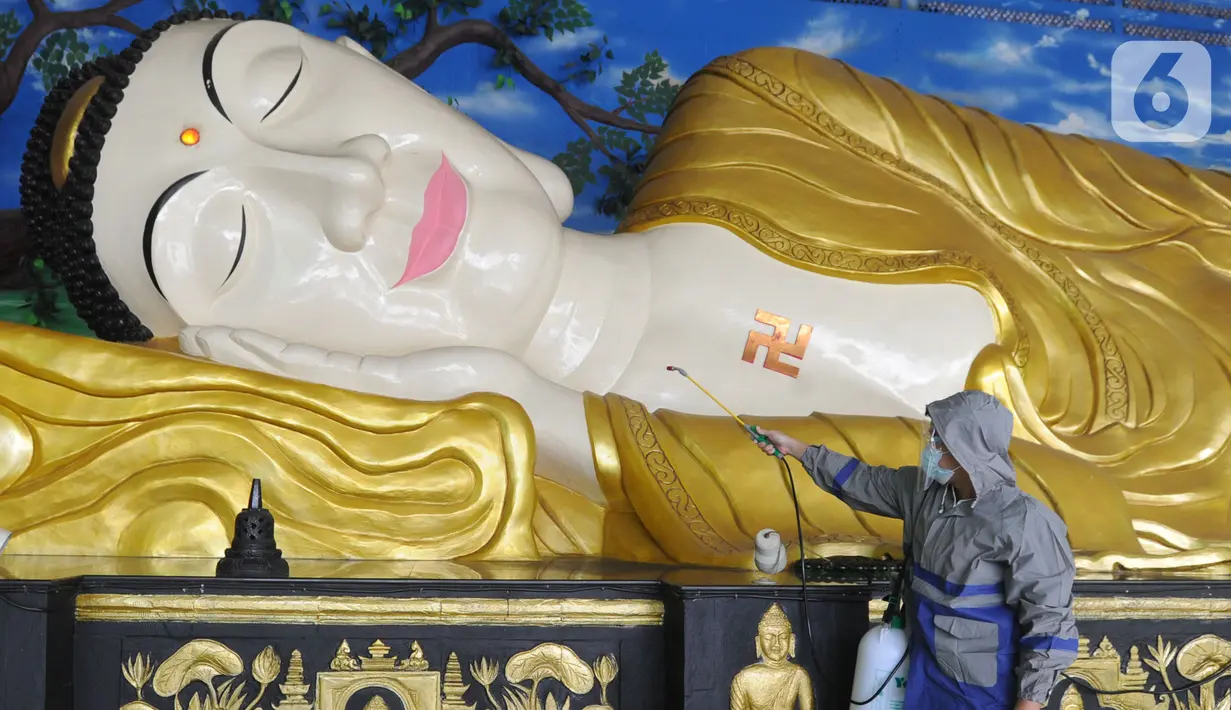 Petugas menyemprotkan cairan disinfektan ke patung Buddha tidur raksasa di Vihara Buddha Dharma dan 8 Posat, Bogor, Jawa Barat, Minggu (7/2/2021). Patung buddha tidur raksasa sepanjang 18 meter dan tinggi 5 meter tersebut dibersihkan setiap tahun menjelang Tahun Baru Imlek. (merdeka.com/Arie Basuki)