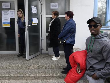 TKA menunggu di depan kantor yang terbuka untuk orang asing yang mengajukan visa, izin kerja, dan izin tinggal di Kroasia, di Zagreb pada 11 April 2023. (AFP/DENIS LOVROVIC)