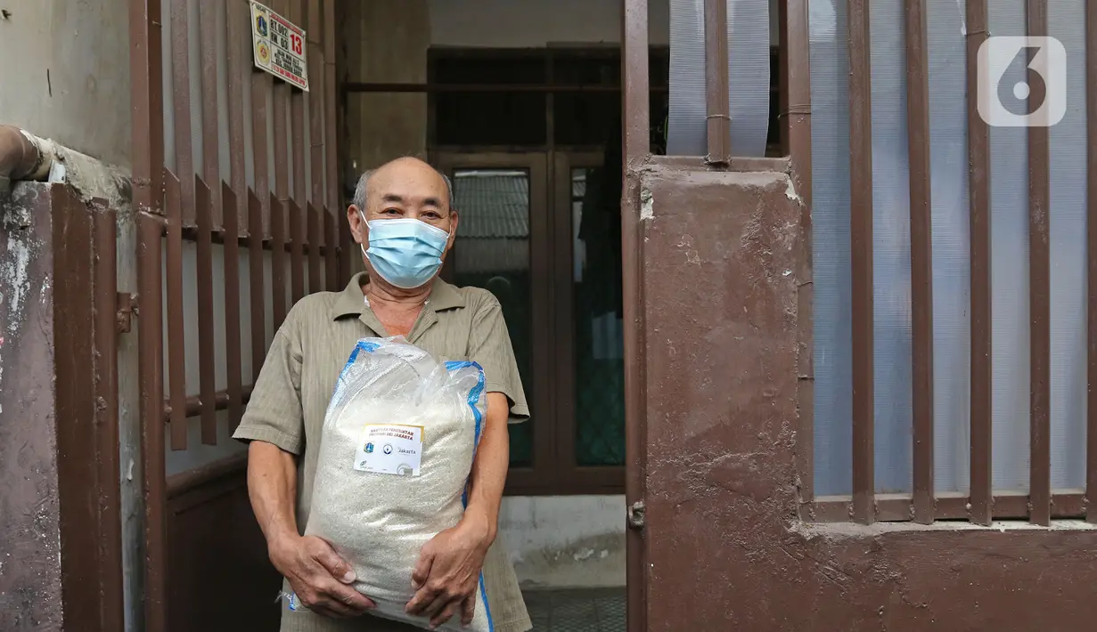 Warga menerima bantuan sosial non tunai berupa beras di kawasan RW 03 Kelurahan Tanah Tinggi, Jakarta, Kamis (29/7/2021). Dinas Sosial DKI kembali mendistribusikan Bantuan Sosial Non Tunai (BSNT) berupa beras mulai 29 Juli-17 Agustus 2021. (Liputan6.com/Herman Zakharia)