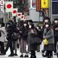 Orang-orang yang mengenakan masker menunggu lampu lalu lintas di penyeberangan pejalan kaki di Shibuya, Tokyo, Jepang, Selasa (5/1/2021). Ibu kota Jepang, Tokyo mengonfirmasi lebih dari 1.200 kasus virus corona COVID-19 baru pada Selasa (5/1). (AP Photo/Eugene Hoshiko)