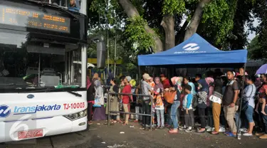 Antrean penumpang menaiki bus tingkat wisata di depan halte Masjid Istiqlal, Jakarta, Minggu (30/4). Warga memanfaatkan hari libur panjang mereka dengan berkeliling Jakarta menggunakan bus tingkat ini secara gratis. (Liputan6.com/Yoppy Renato)