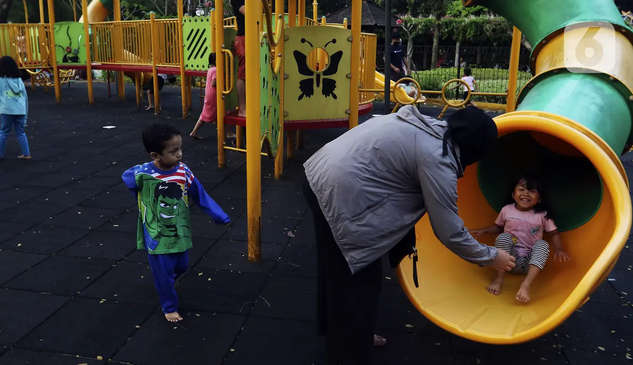 Anak-anak didampingi orangtua bermain di RPTRA Bhineka Jakarta Selatan, Sabtu (30/7/2022). Selain menjadi alternatif mengisi libur bersama keluraga, taman juga menjadi ruang bagi warga untuk berinteraksi sosial sekaligus mengeduksi anak untuk bermain bersama teman-teman dengan wahana yang tersedia. (Liputan6.com/Johan Tallo)