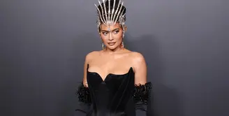 Kylie Jenner jelas menjadi pusat perhatian dengan penampilannya kali ini. Luar biasa dalam balutan gaun Mugler berwarna hitam, Kylie Jenner mengenakan head-piece dan gloves yang senada dengan off-the-shoulder dress-nya.