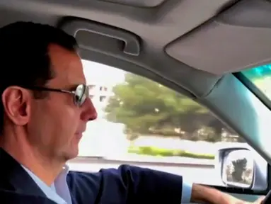 Gambar dari video pada Minggu (18/3), Presiden Suriah Bashar al-Assad mengemudi sendiri mobilnya melalui daerah-daerah yang baru dibebaskan di pinggiran Damaskus untuk mengunjungi pasukan garis depan di Ghouta timur. (Syrian Presidency Facebook Page/AP)