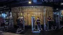 Orang-orang berolahraga dengan plastik penyekat untuk membatasi jarak antar pengunjung di sebuah tempat gym di Surabaya, Rabu (21/10/2020). Pusat kebugaran itu dibuka dengan menerapkan protokol kesehatan sebagai pencegahan COVID-19. (Juni Kriswanto / AFP)