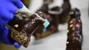 Pembuat roti menghias kue cokelat Paskah berbentuk domba tradisional dengan masker di toko roti Schuerener Backparadies, Dortmund, Jerman, Rabu (8/4/2020). Pembuatan kue Paskah dengan masker bertepatan dengan pandemi virus corona COVID-19. (Ina FASSBENDER/AFP)