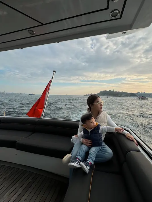 Menaiki boat, Baby Issa mengenakan long sleeve putih dan light jeans. Puffy vest navy melapisi outfit simple-nya untuk menghalau angin kencang. [@nikitawillyofficial94]