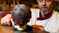 Pembuat cokelat, Jean-François Pre menyiapkan telur paskah berbentuk seperti Virus Corona di tokonya di Landivisiau, Prancis, 7 Maret 2020. Cokelat ini terbuat dari cokelat putih yang diberikan pewarna hitam serta dipadukan dengan kacang almond yang diwarnai merah. (Damien MEYER/AFP)