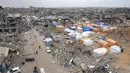 Warga Palestina yang mengungsi mendirikan tenda-tenda permukiman di tengah-tengah puing-puing bangunan yang hancur akibat serangan Israel. (Bashar TALEB/AFP)