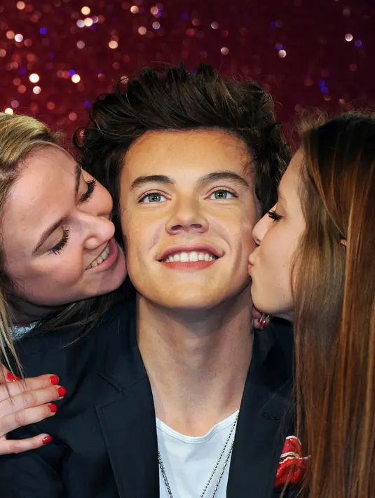 Penggemar wanita One Direction berpose mencium patung lilin dari salah satu bintang One Direction, Harry Styles, di Madame Tussauds di London, Inggris (18/4/2013). (Bintang/EPA)