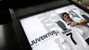 Seorang suporter memperlihatkan jersey Juventus atas nama Cristiano Ronaldo di depan toko resmi klub di Turin, Selasa (10/7). Ronaldo akan menerima gaji hingga 30 juta euro (Rp 504 miliar) per musim dari I Bianconeri. (AFP PHOTO / Isabella Bonottovv)