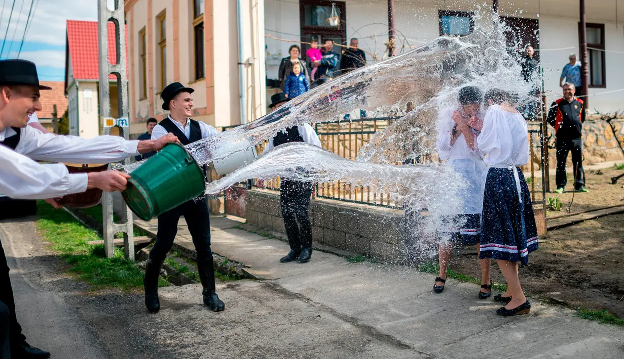 Para pria berkostum rakyat Szekler Bukovina menyiram air ke seorang wanita muda di Ciko, selatan Budapest, Senin (3/4). Tradisi Paskah populer di Hungaria ini dilakukan pada Senin Paskah yang juga dikenal dengan nama Ducking Monday (Tamas Soki/MTI via AP)