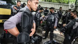 Personel Brimob bersiap mengenakan perlengkapan pelindung diri di Kawasan Bundaran HI, Jakarta, Selasa (13/10/2020). Sebanyak kurang lebih 12 ribu personel gabungan TNI, Polri dan Pemprov DKI Jakarta diterjunkan mengawal aksi tolak Undang-Undang Cipta Kerja Omnibus Law. (Liputan6.com/Faizal Fanani)