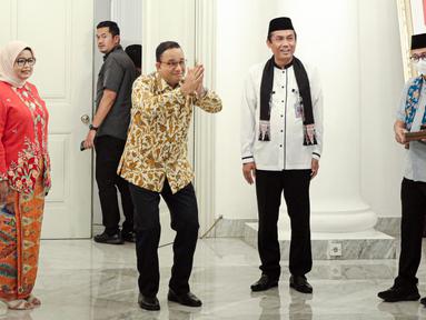 Gubernur DKI Jakarta Anies Baswedan (kedua kiri) ditemani istri Fery Farhati (kiri) memberi isyarat saat menyapa para Aparatur Sipil Negara (ASN) di Balai Kota DKI Jakarta, Jumat (14/10/2022). Di hari terakhir menjabat sebagai Gubernur DKI Jakarta, Anies Baswedan menyempatkan diri untuk menyapa ASN di Balai Kota. (Liputan6.com/Faizal Fanani)